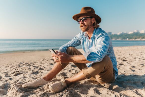young-attractive-hipster-man-sitting-beach-by-sea-summer-vacation-min