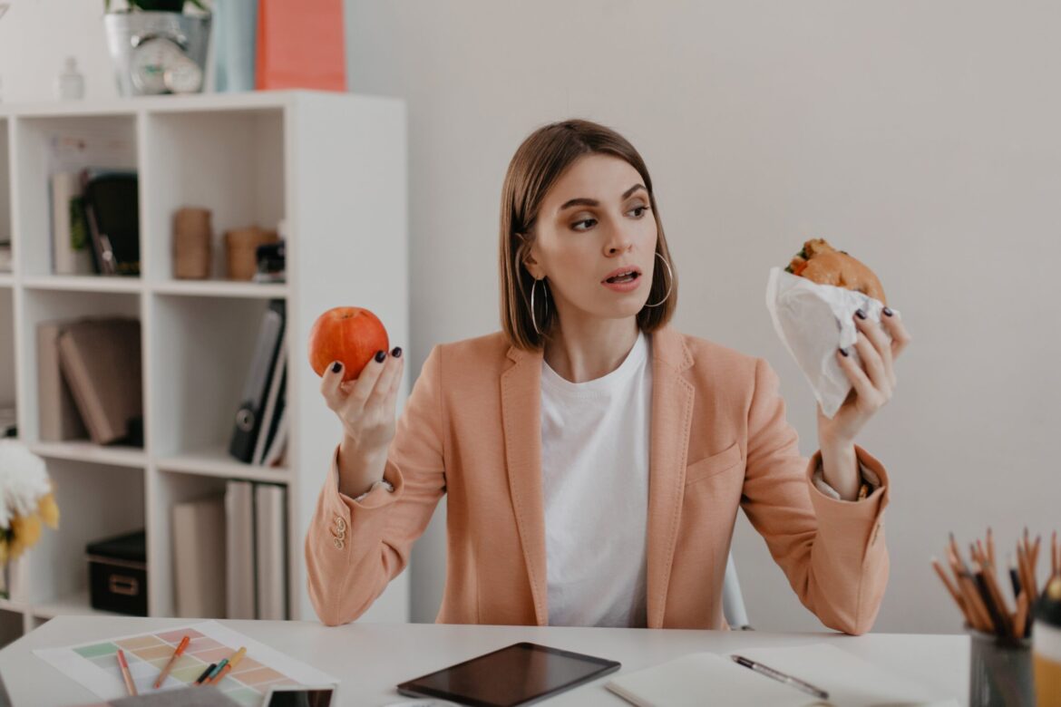 picture-business-woman-pink-jacket-sitting-workplace-woman-choose-tasty-burger-wholesome-apple-min
